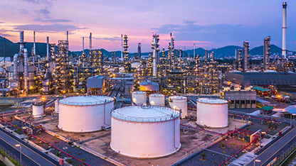 Large refinery showing tanks, towers, lights and mountains in distance